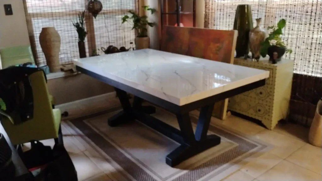A modern dining table with a white marble top and black legs in a cozy dining area.