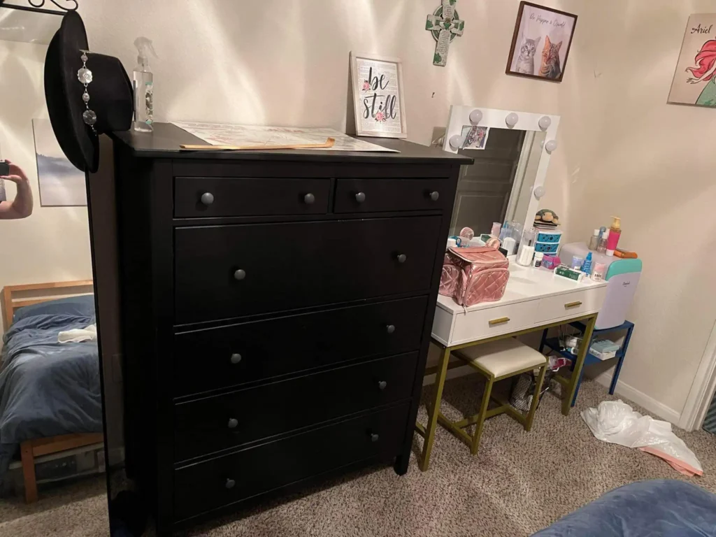 A stylish black dresser and white vanity in a cozy bedroom setting.