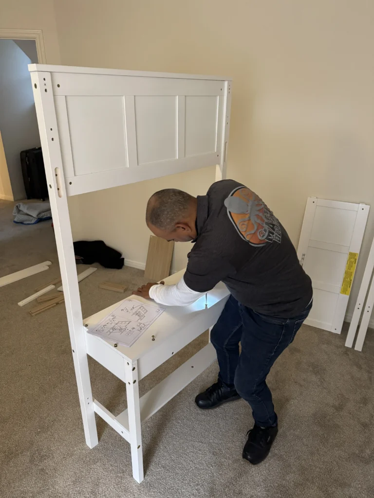 A person assembling white furniture with instruction manual.