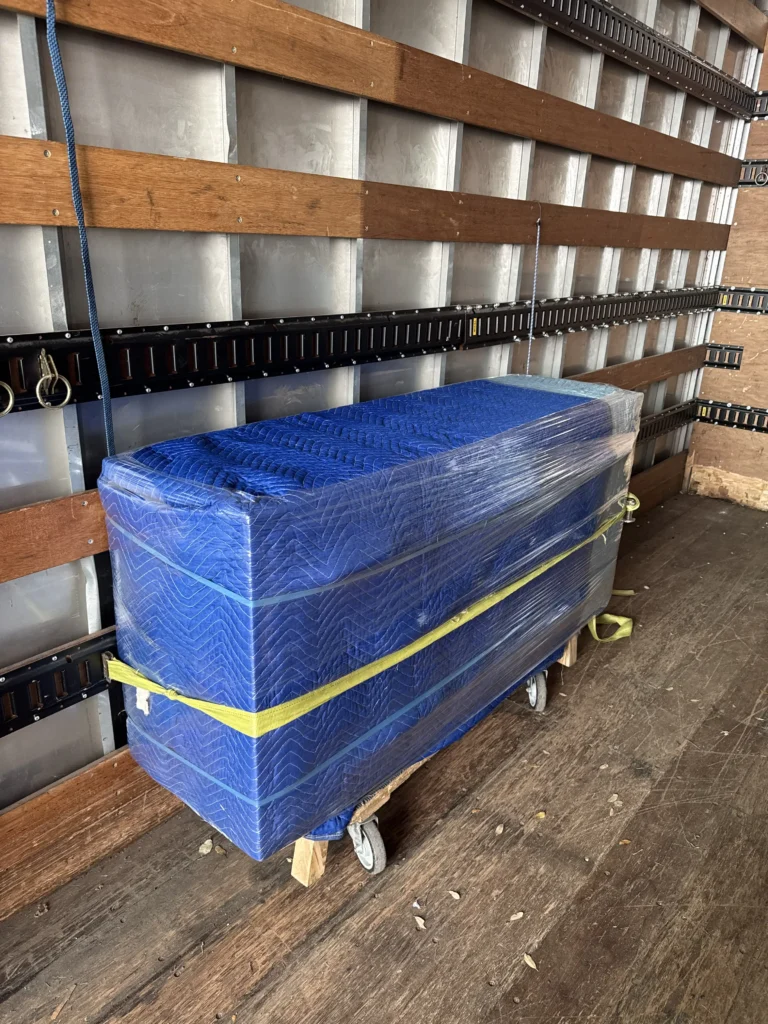 Blue moving blankets on a wooden pallet, ready for transport in a truck.