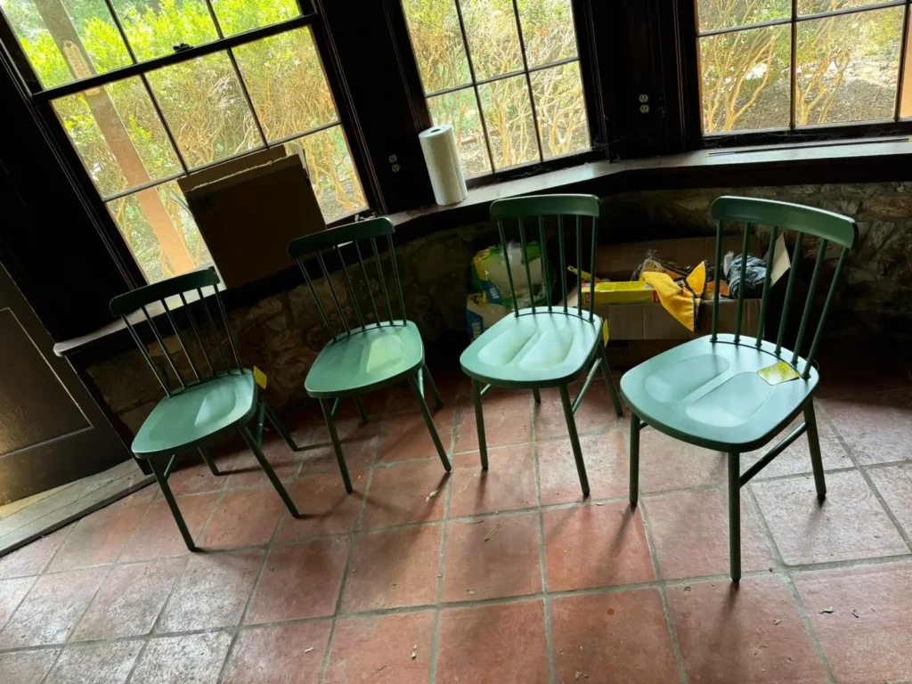 Four green dining chairs arranged in a cozy living room setting.